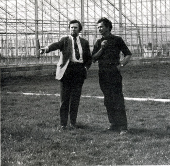 Picture of Mr Norman Warner talking to one of his employees in front of one of the battery of huge greenhouses